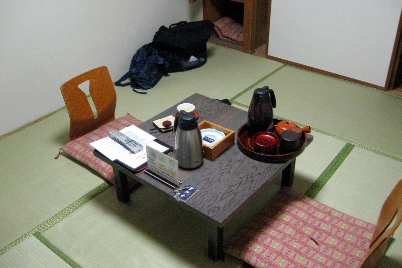 Stanza giapponese con pavimento in tatami, tavolino basso, cuscino e vassoio da tè
