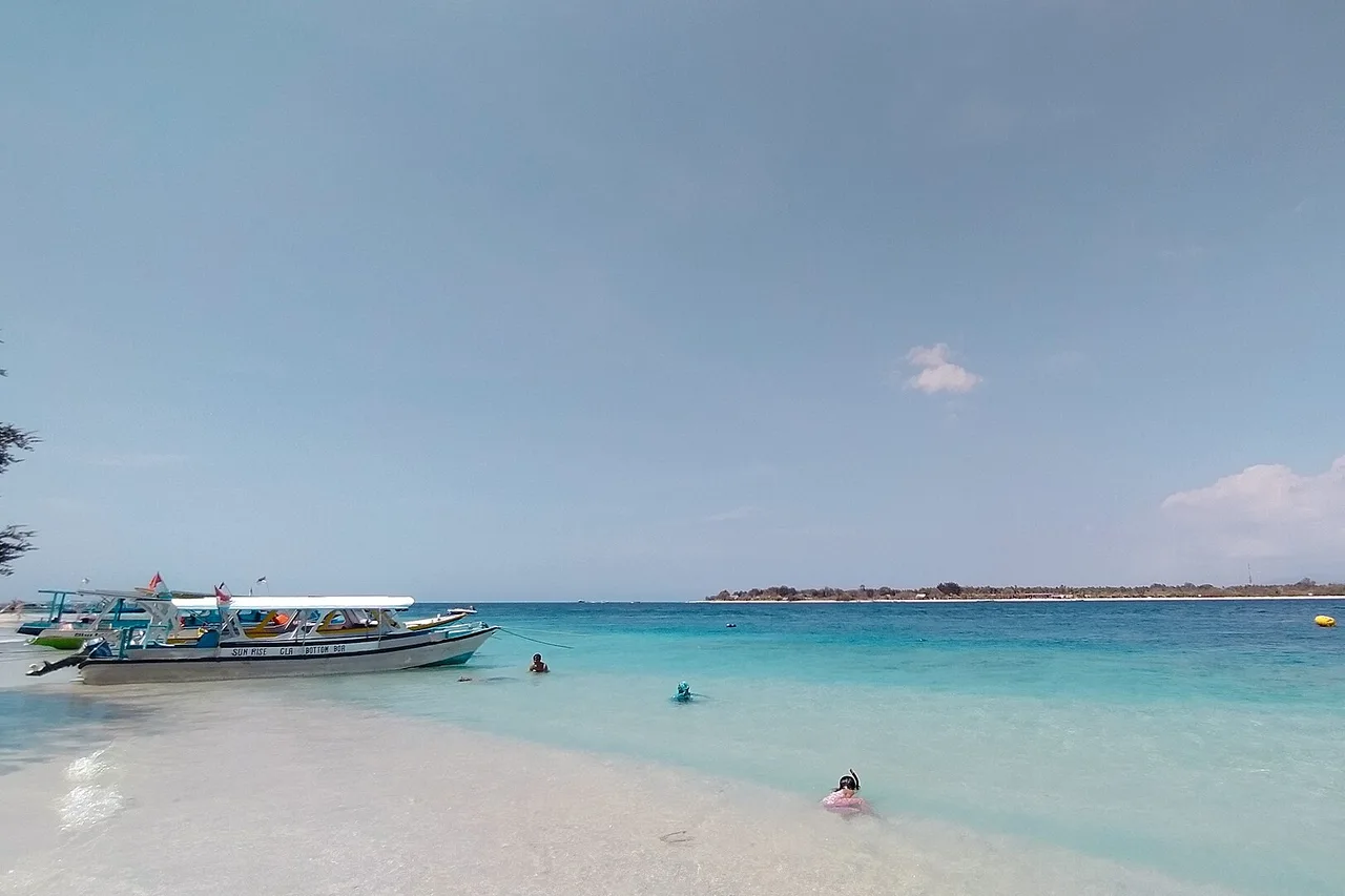 Ostküste von Gili Trawangan: klares, flaches Wasser, ankernde Boote, eine schwimmende Person