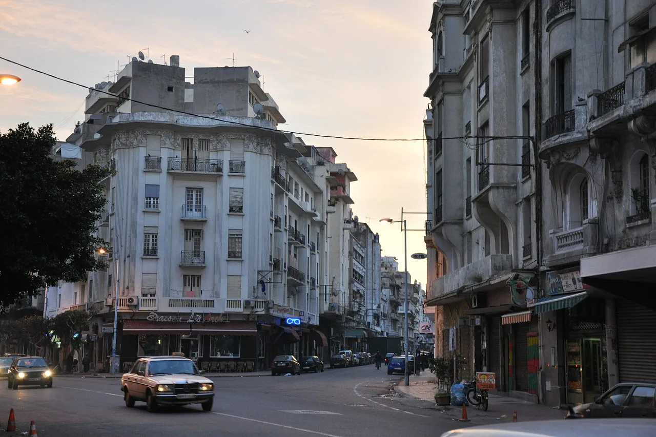 Une vieille Mercedes W123 beige, le taxi le plus répandu du Maroc, en mouvement dans la rue