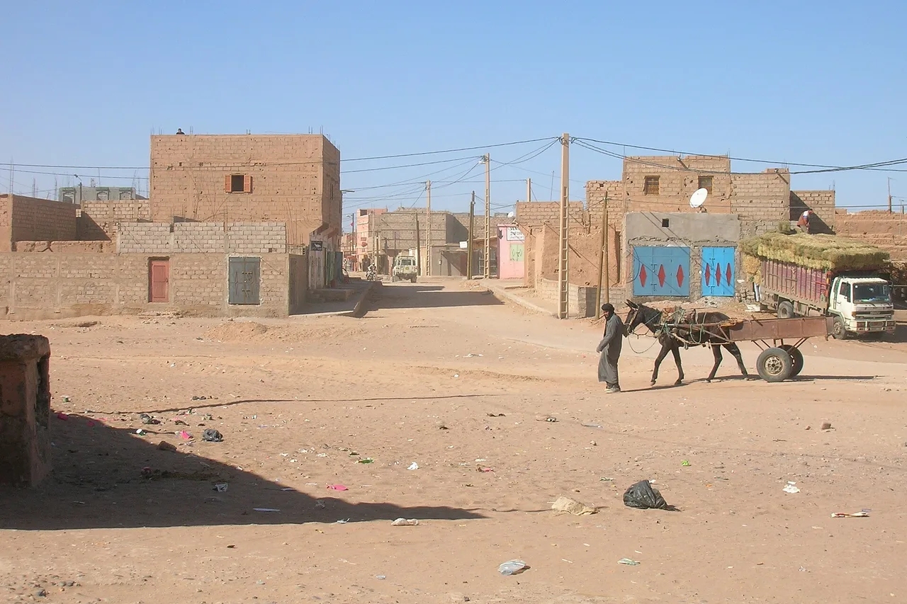Una calle de tierra en M’Hamid el Ghizlane, con un carro tirado por un burro y un camión, al borde del Sáhara
