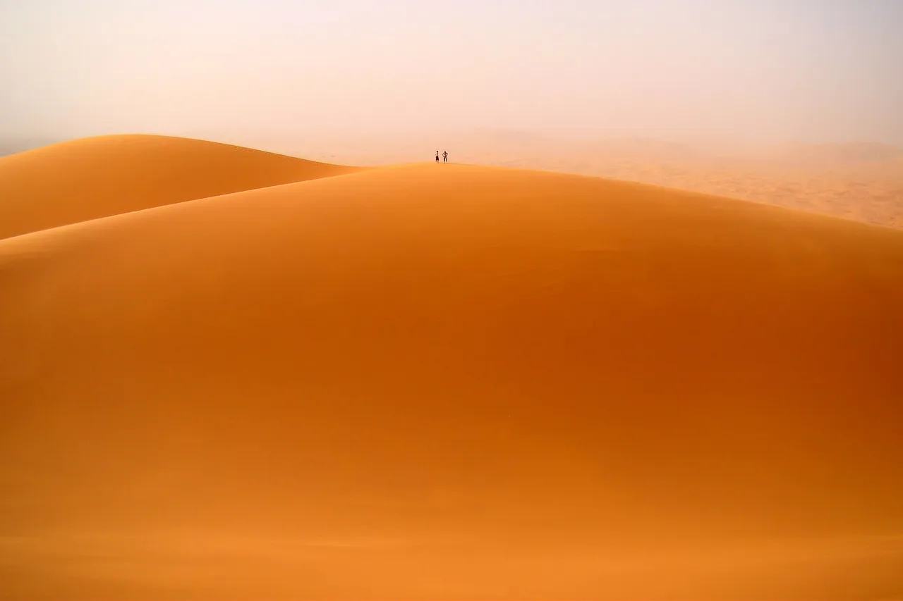 A great orange dune at Merzouga, with two tiny figures on the crest