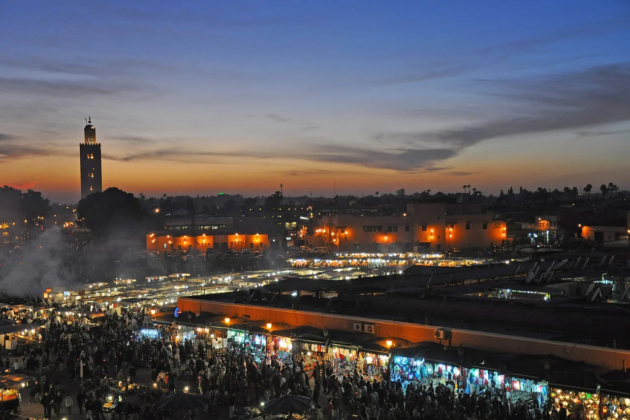La piazza Jemaa el-Fna a Marrakech al crepuscolo, il fumo delle bancarelle e sullo sfondo il minareto della Koutoubia