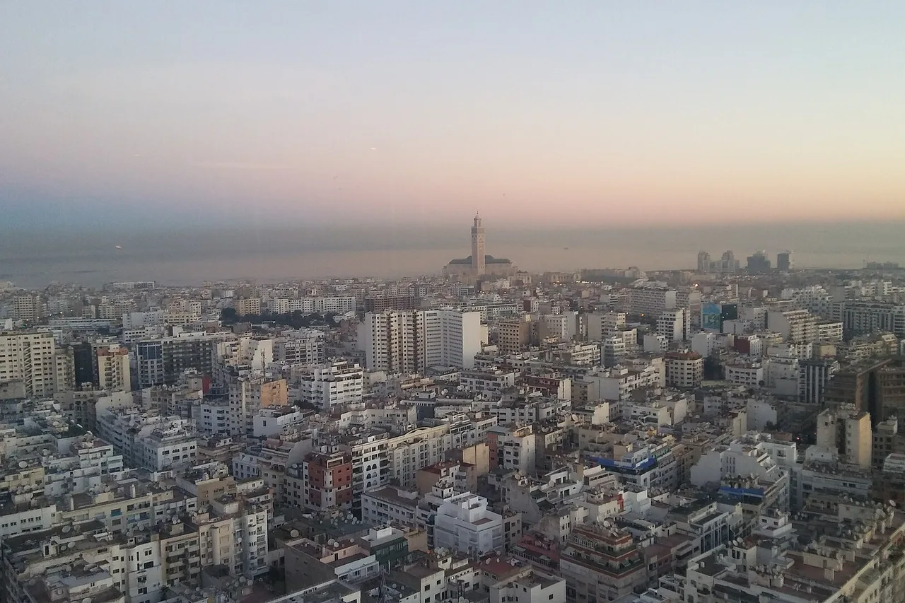 Vista sobre los tejados de Casablanca al anochecer, con la mezquita Hassan II junto al mar en el horizonte