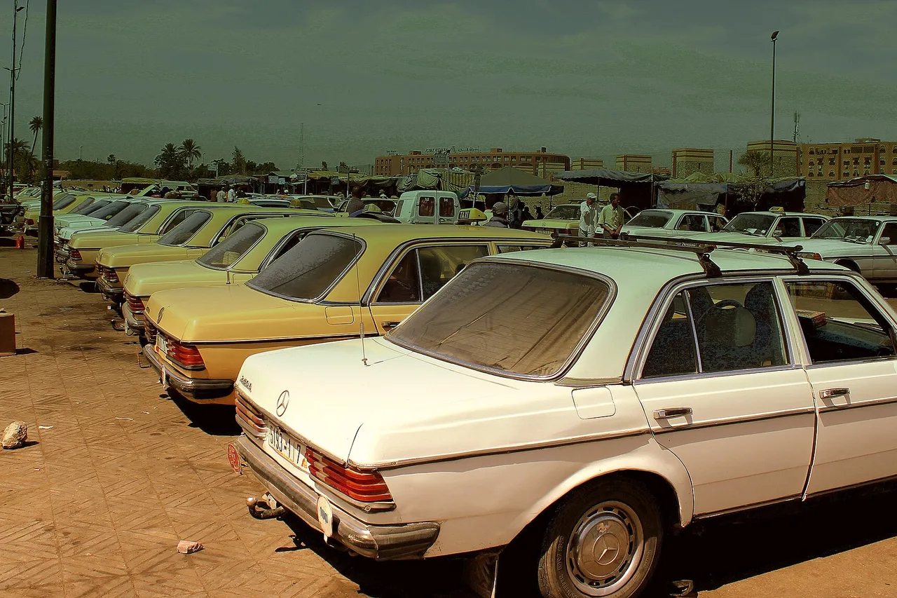 Fila di vecchi taxi Mercedes beige e bianchi in un posteggio di Marrakech, foto del 2013