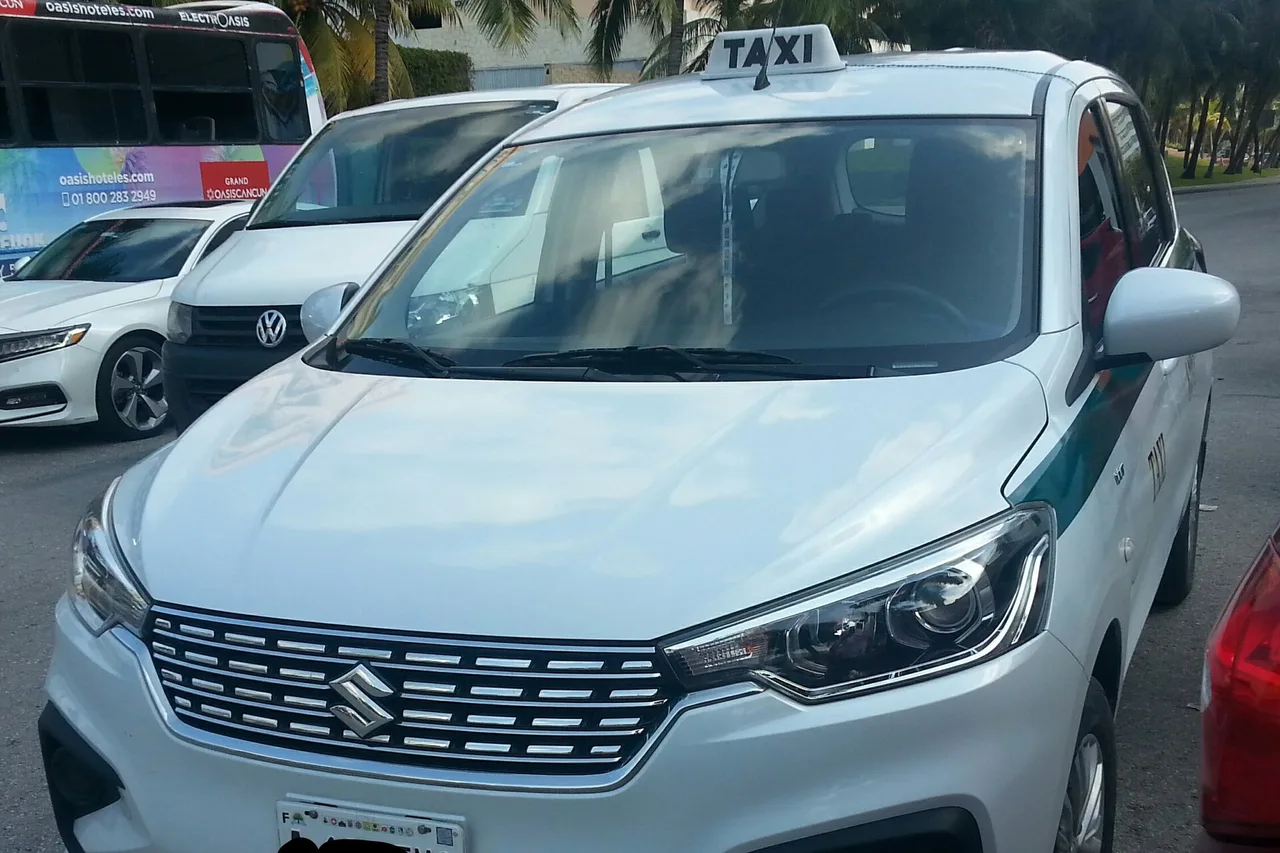 Weißes Taxi mit Dachschild auf einem Parkplatz in Cancún