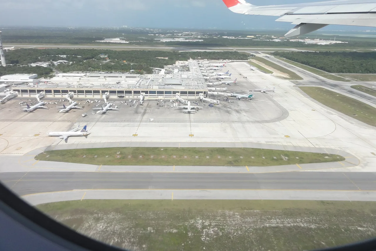Blick aus dem Flugzeugfenster beim Anflug auf das Terminal des Flughafens Cancún mit abgestellten Maschinen
