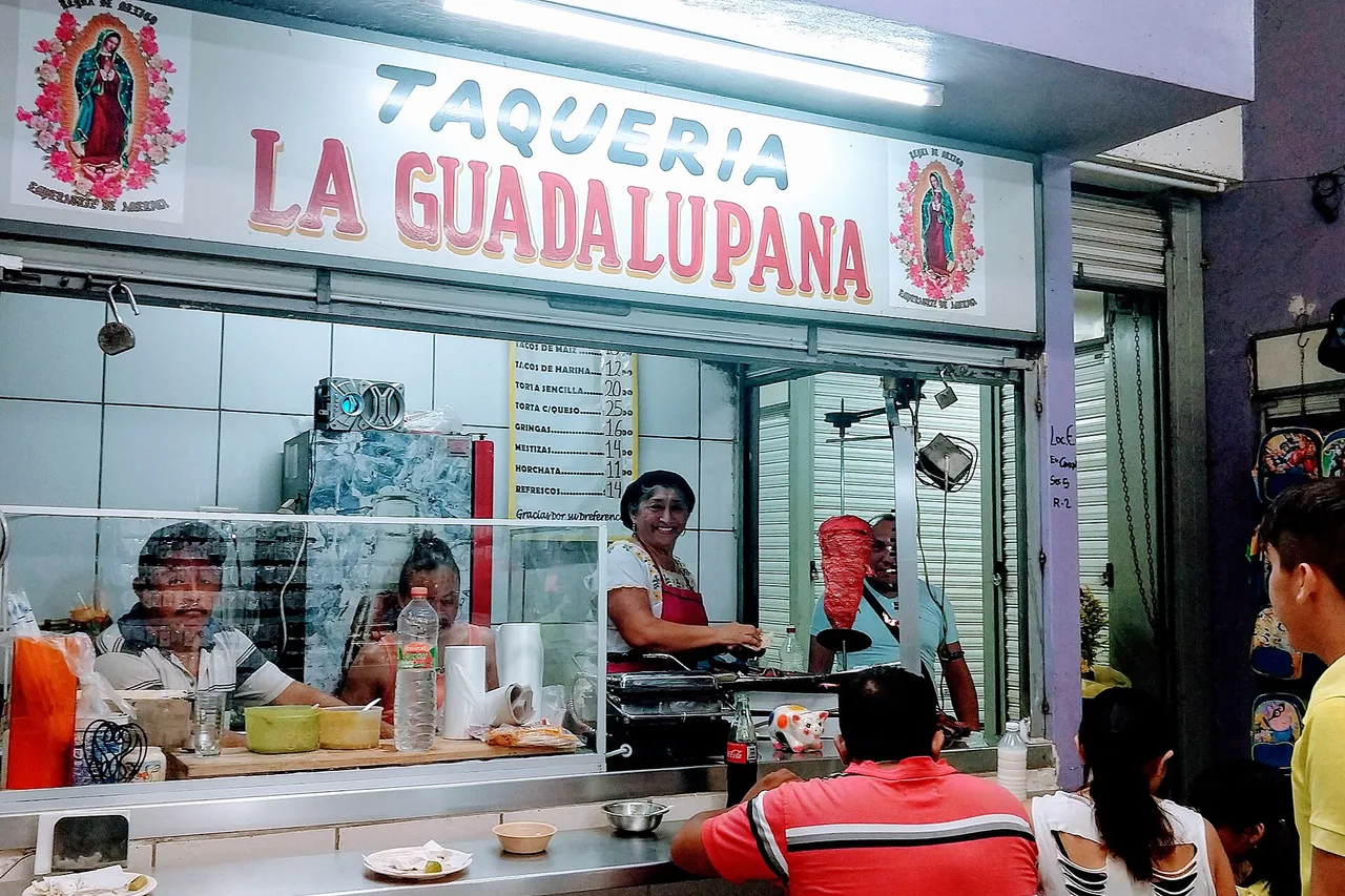 Ein Fleischspieß al pastor vor seinem senkrechten Grill an einem mexikanischen Marktstand