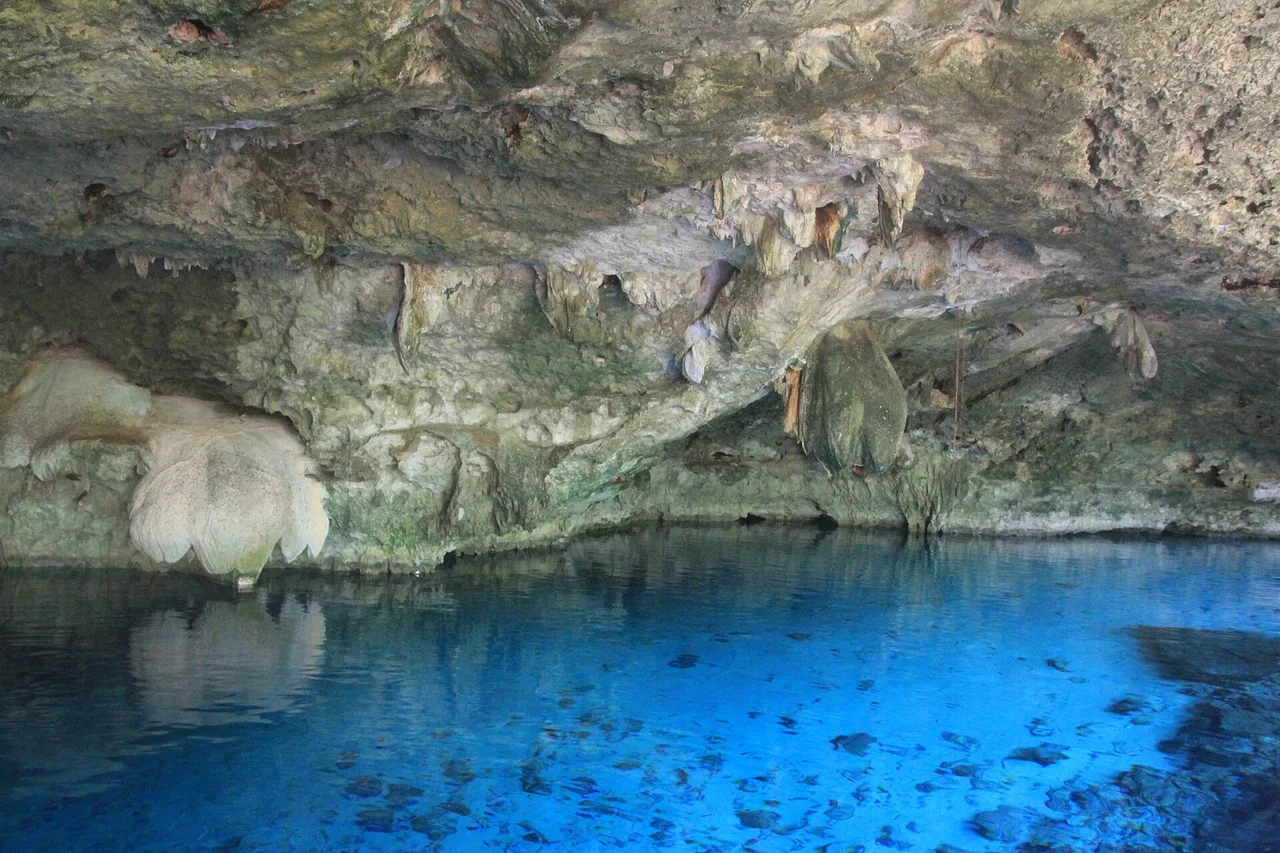 L’eau limpide et bleue du cénote Dos Ojos sous une voûte rocheuse basse, près de Tulum
