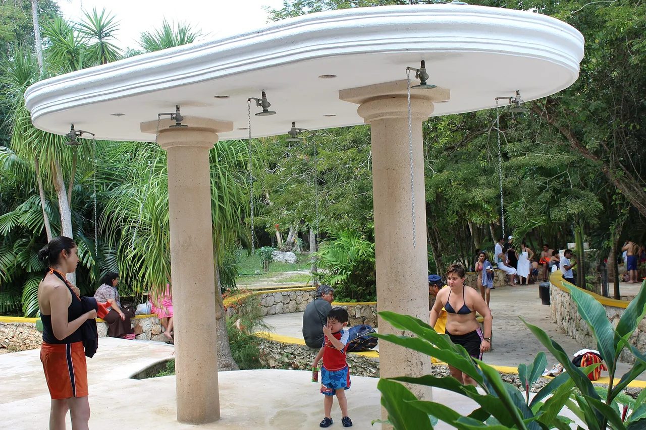 Le pavillon de douches d’un cénote aménagé du Yucatán, des visiteurs en maillot autour