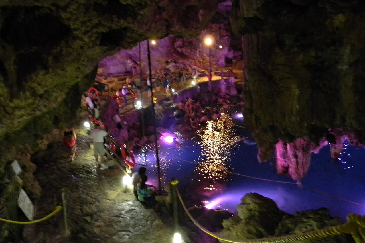 Des visiteurs font la queue sur la passerelle éclairée d’un cénote en grotte du Yucatán