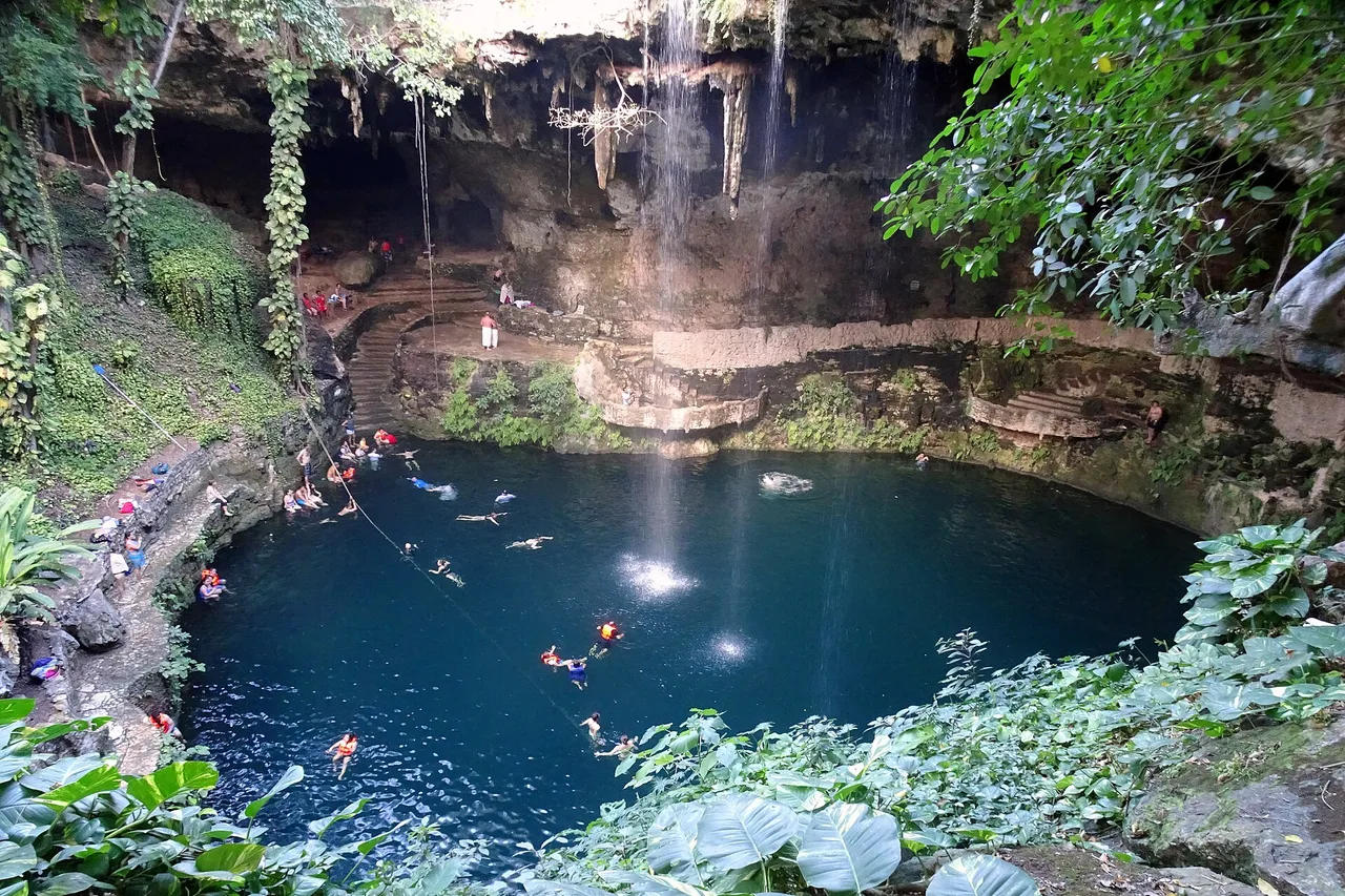 Le cénote Zací à Valladolid, un puits à ciel ouvert cerclé de falaise, des baigneurs dans l’eau sombre