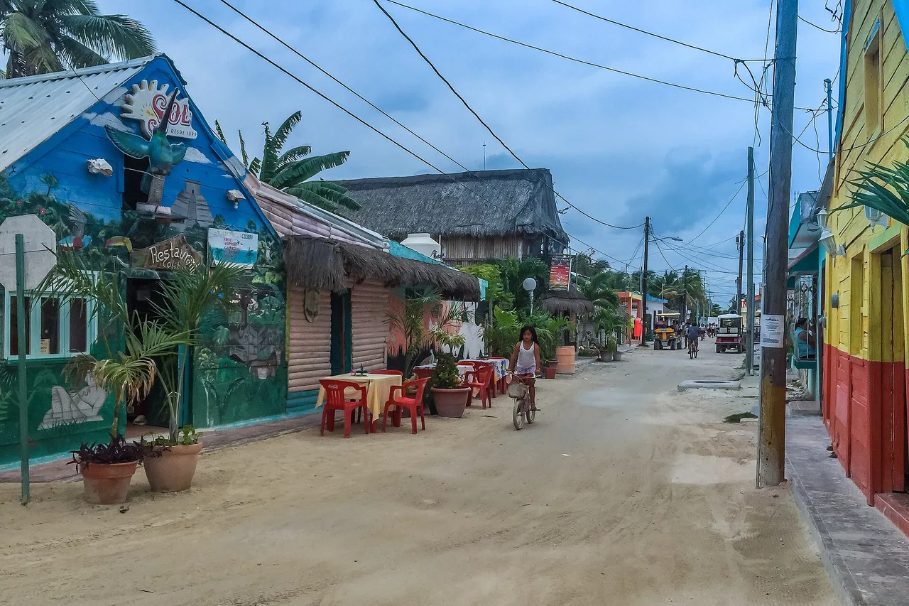 A sand street in Holbox lined with colourful houses and palapas, bicycles leaning against a wall