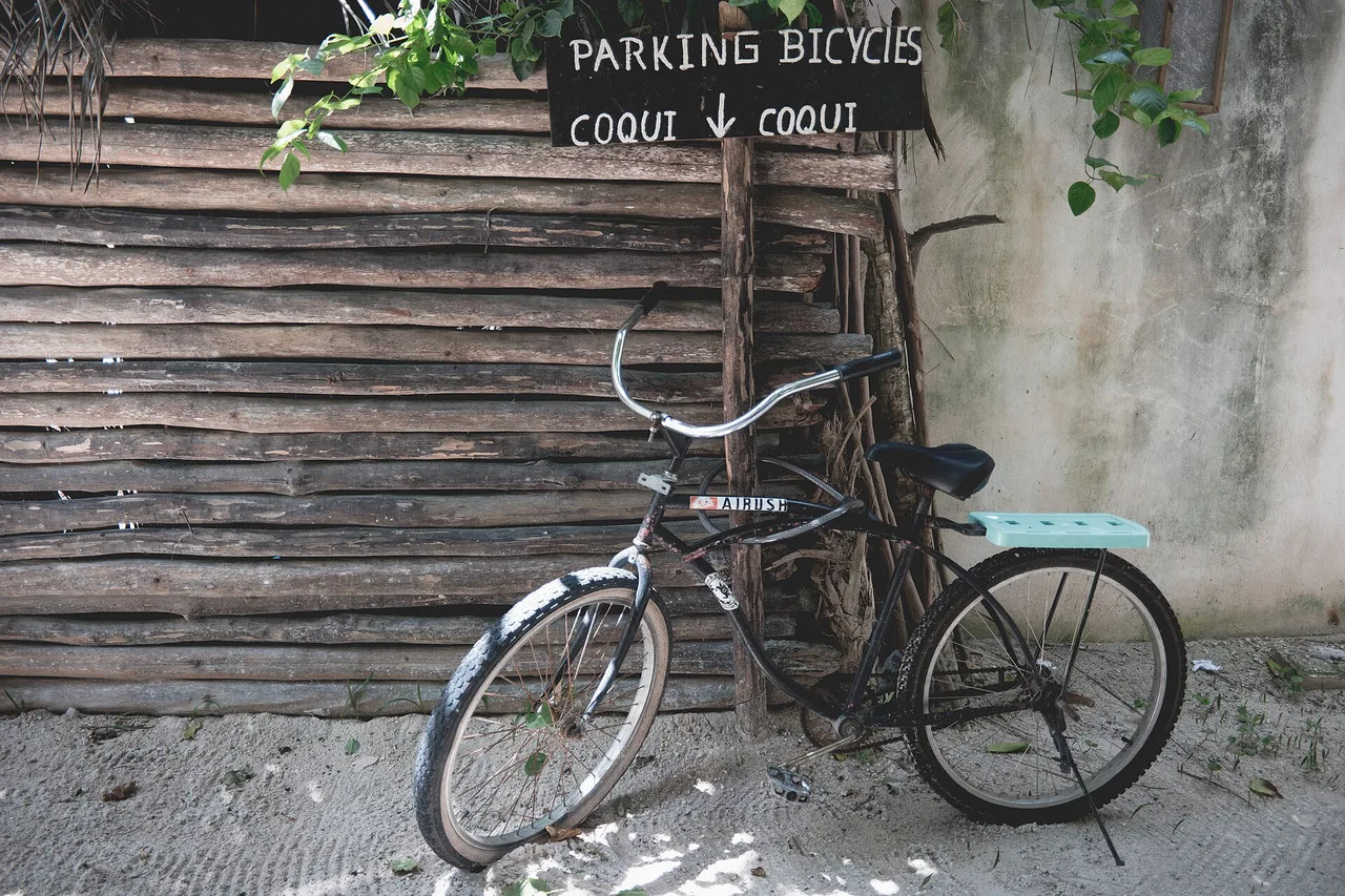 Una bicicleta apoyada en el muro de madera de un hotel de la carretera de la playa de Tulum