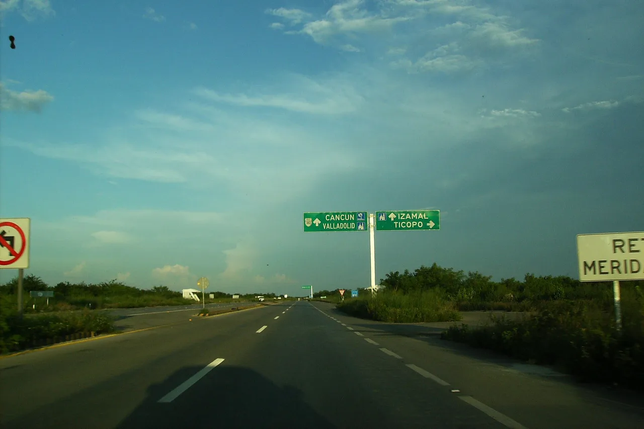 Vista dal parabrezza sull’autostrada 180 dello Yucatán, cartelli verdi verso Mérida e Cancún