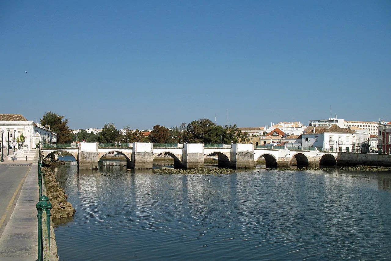 Die alte Brücke von Tavira über den Fluss Gilão vor den niedrigen Häusern der Altstadt