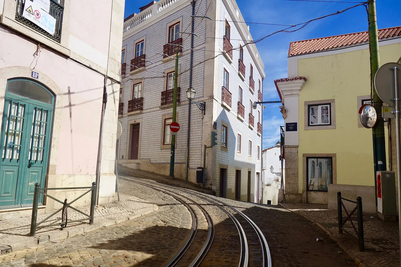 A yellow tram on line 28 climbing a narrow street in the Alfama district of Lisbon