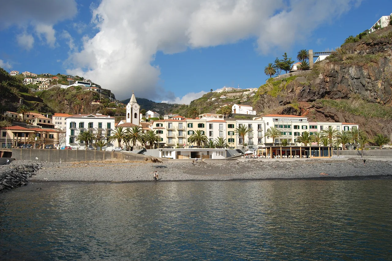 Il lungomare di Ponta do Sol con case bianche, palme e una spiaggia di ciottoli