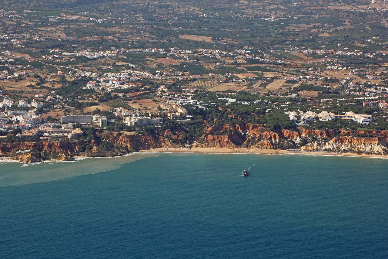 Aerial view of the ochre cliffs of Praia da Falésia and the long strip of sand below the hotels of Olhos de Água