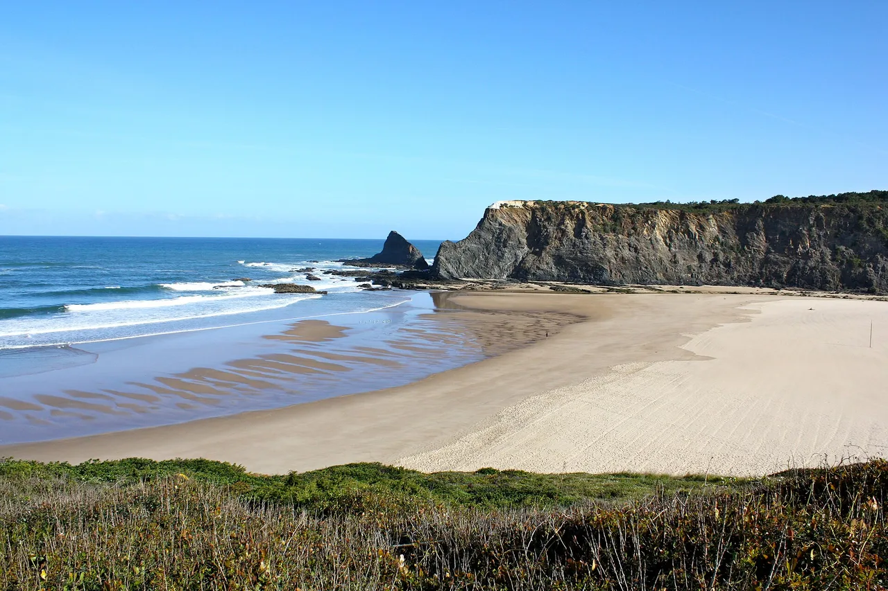 Odeceixe beach between dark cliffs and a river mouth, on the west coast of the Algarve