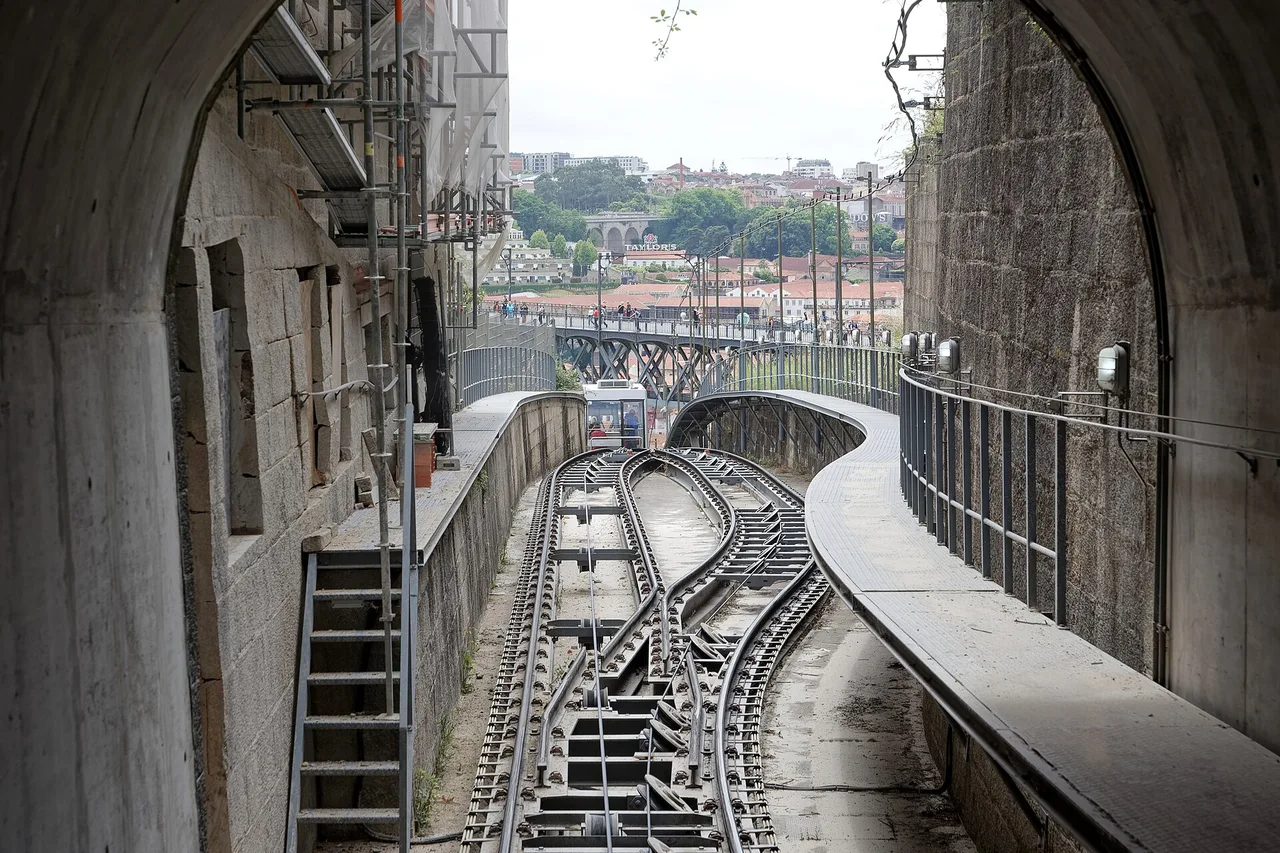 La cabina acristalada del Funicular dos Guindais subiendo junto a la muralla, en Oporto