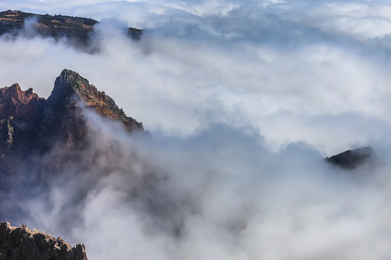 Nuvole dense passano davanti alle ripide pareti rosse del Pico do Areeiro