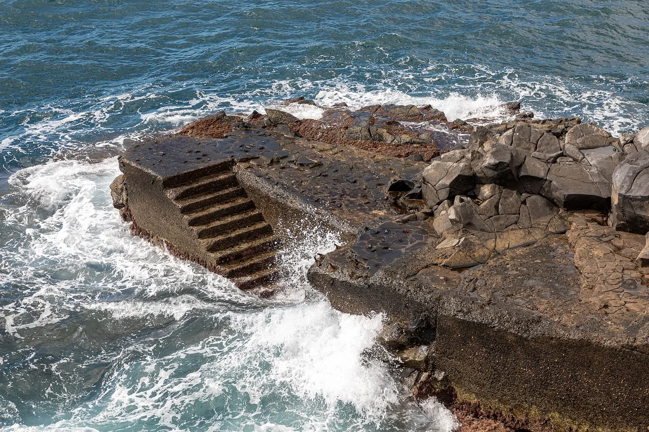 Una scala scende dalle rocce laviche del Lido, a Funchal, direttamente tra le onde dell'Atlantico