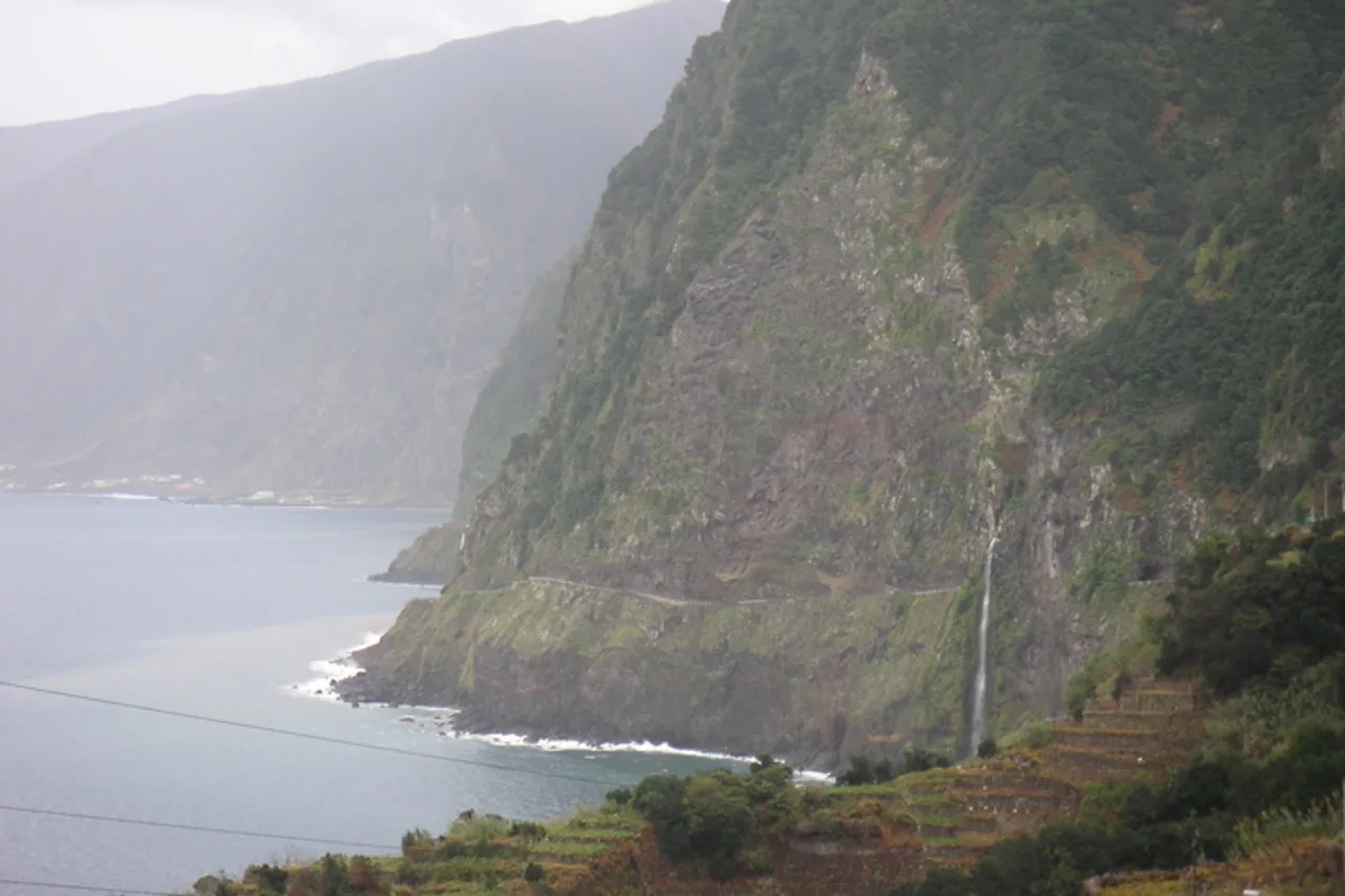 Una cascata scende dalla scogliera accanto alla vecchia strada costiera vicino a Porto Moniz