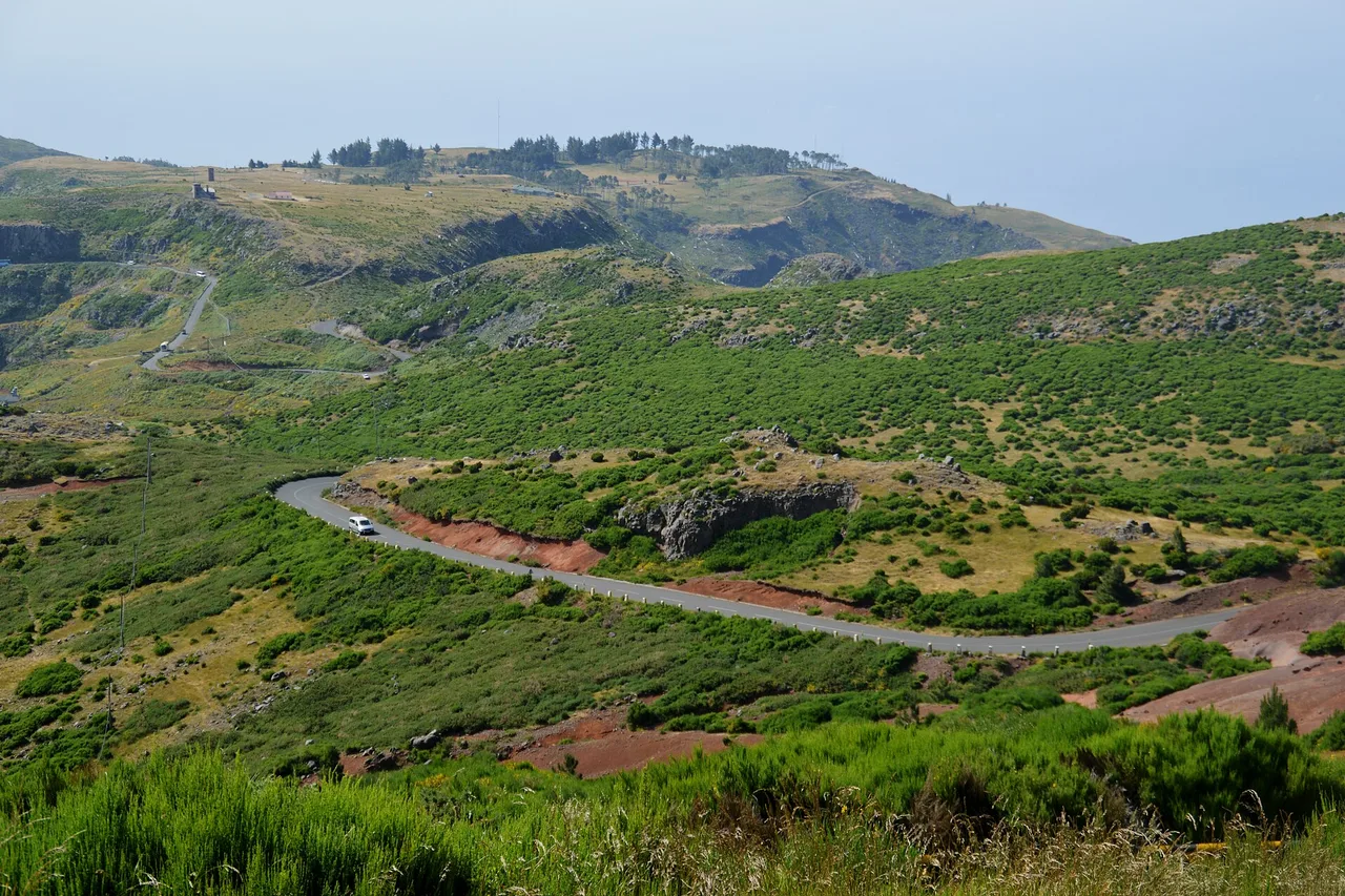 Una strada di montagna tortuosa sale tra pendii verdi verso il Pico do Arieiro, a Madeira