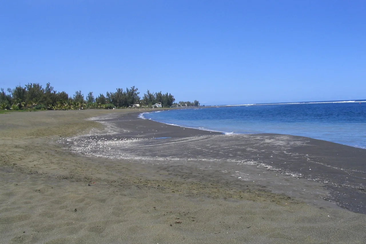 Der schwarze Vulkansandstrand von Étang-Salé-les-Bains, gesäumt von Filao-Bäumen, La Réunion