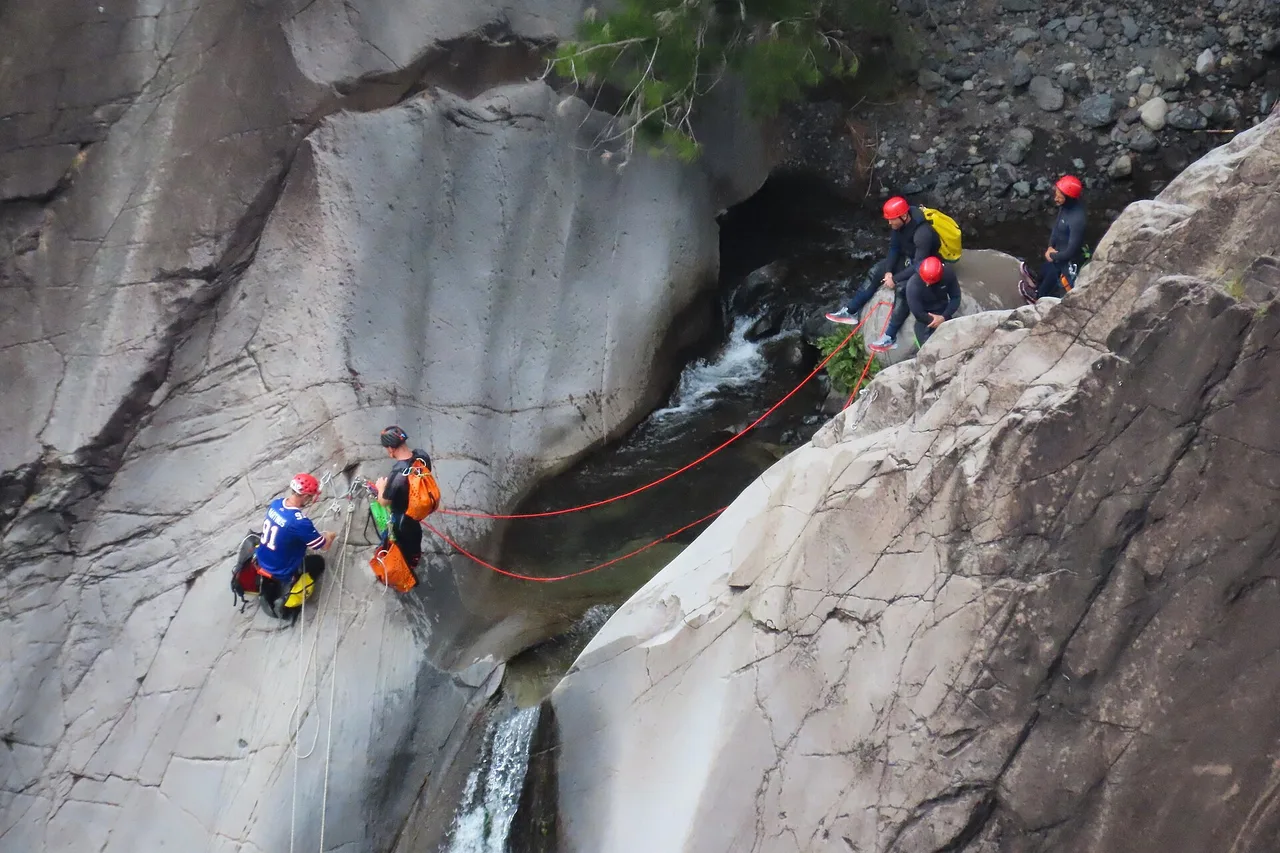 Canyonistes casqués descendant en rappel la ravine Fleurs Jaunes à Cilaos, La Réunion