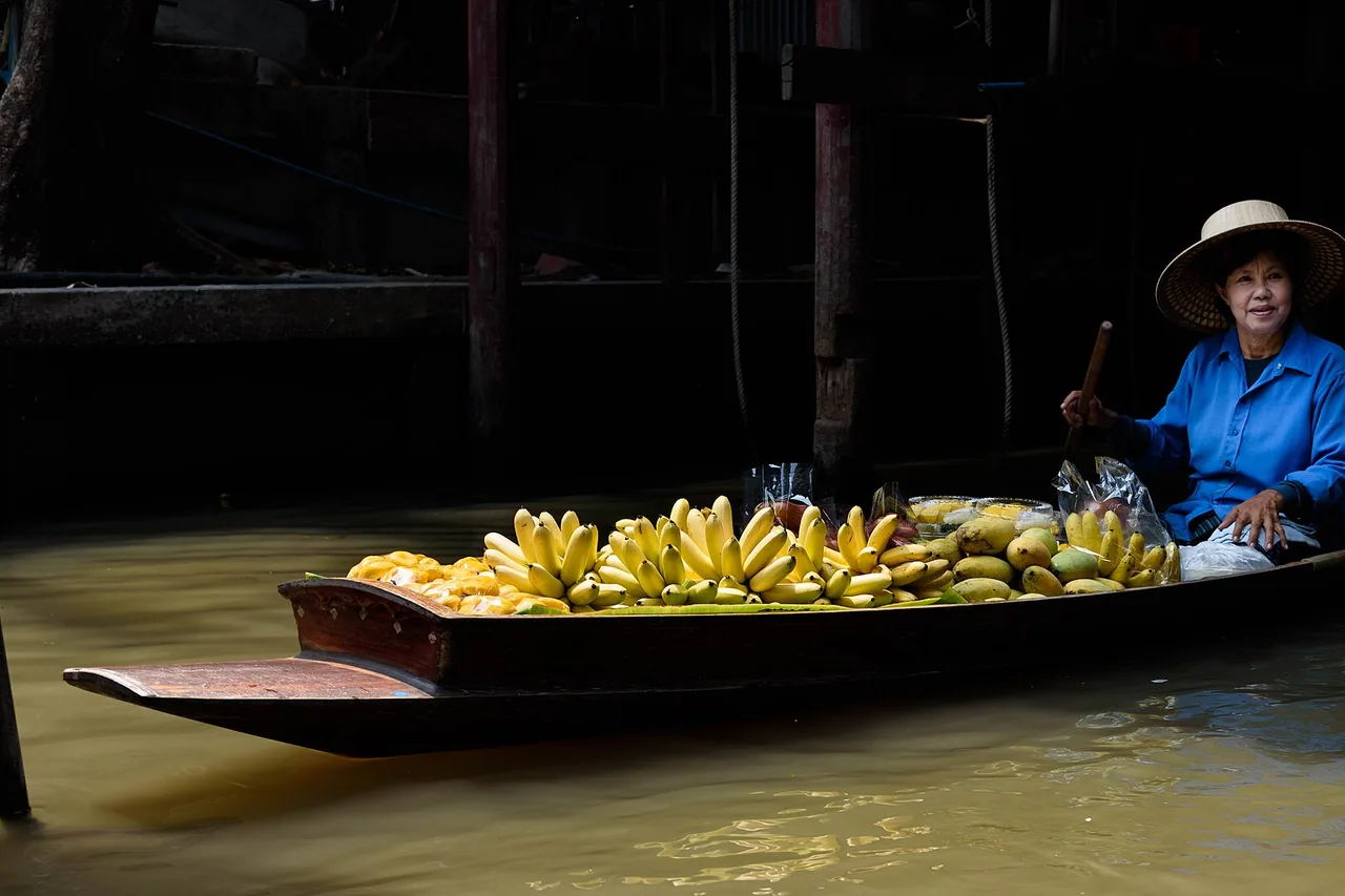 Eine Frau verkauft Bananen von ihrem Boot auf einem schwimmenden Markt, Thailand