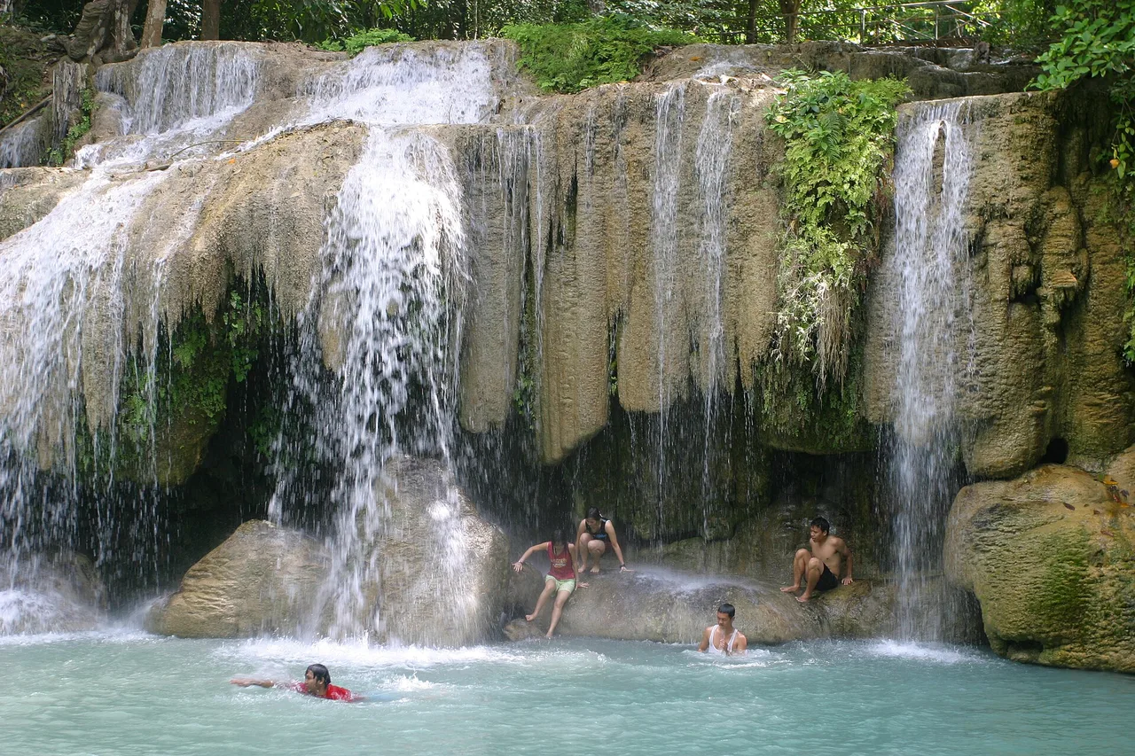 Badende im türkisfarbenen Becken des Erawan-Wasserfalls, Provinz Kanchanaburi, Thailand