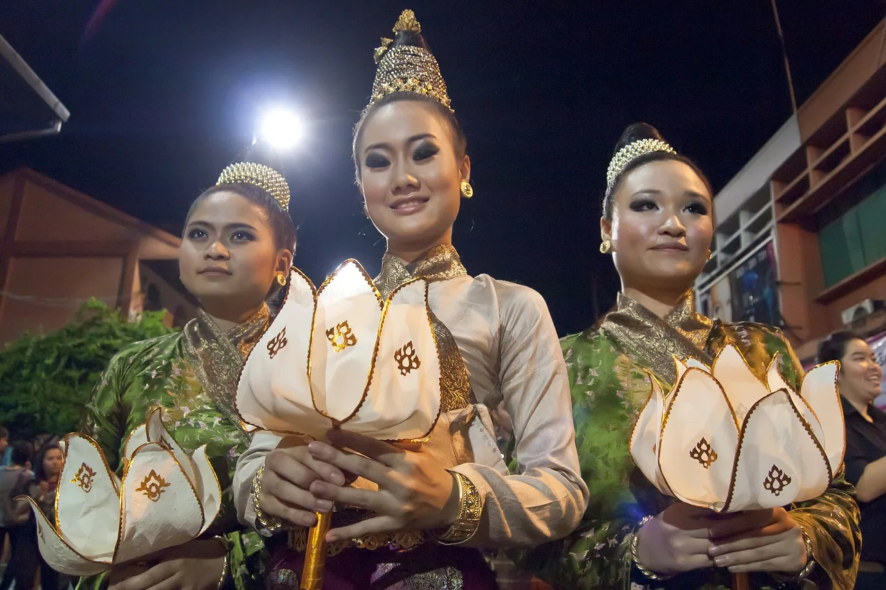 Tres mujeres con traje lanna llevando krathong en forma de loto durante la fiesta de las luces