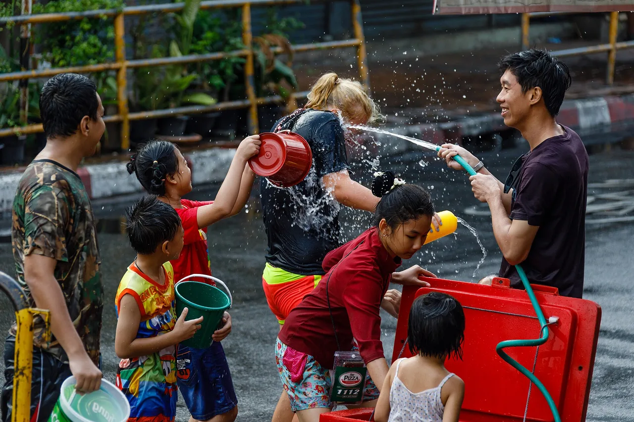 Vecinos mojándose con manguera y cubos en una calle de Chiang Mai durante Songkran