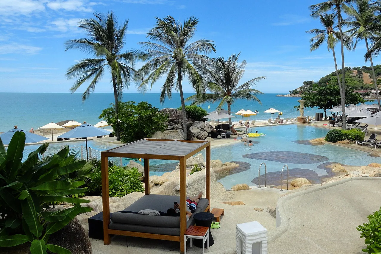 Pool, Liege unter Palmen und Meer im Hintergrund am Chaweng Noi, Koh Samui