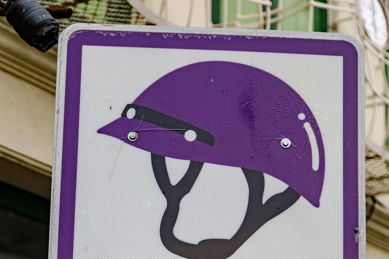 Ein violettes thailändisches Verkehrsschild mit einem Helm-Piktogramm, aufgenommen auf Phuket