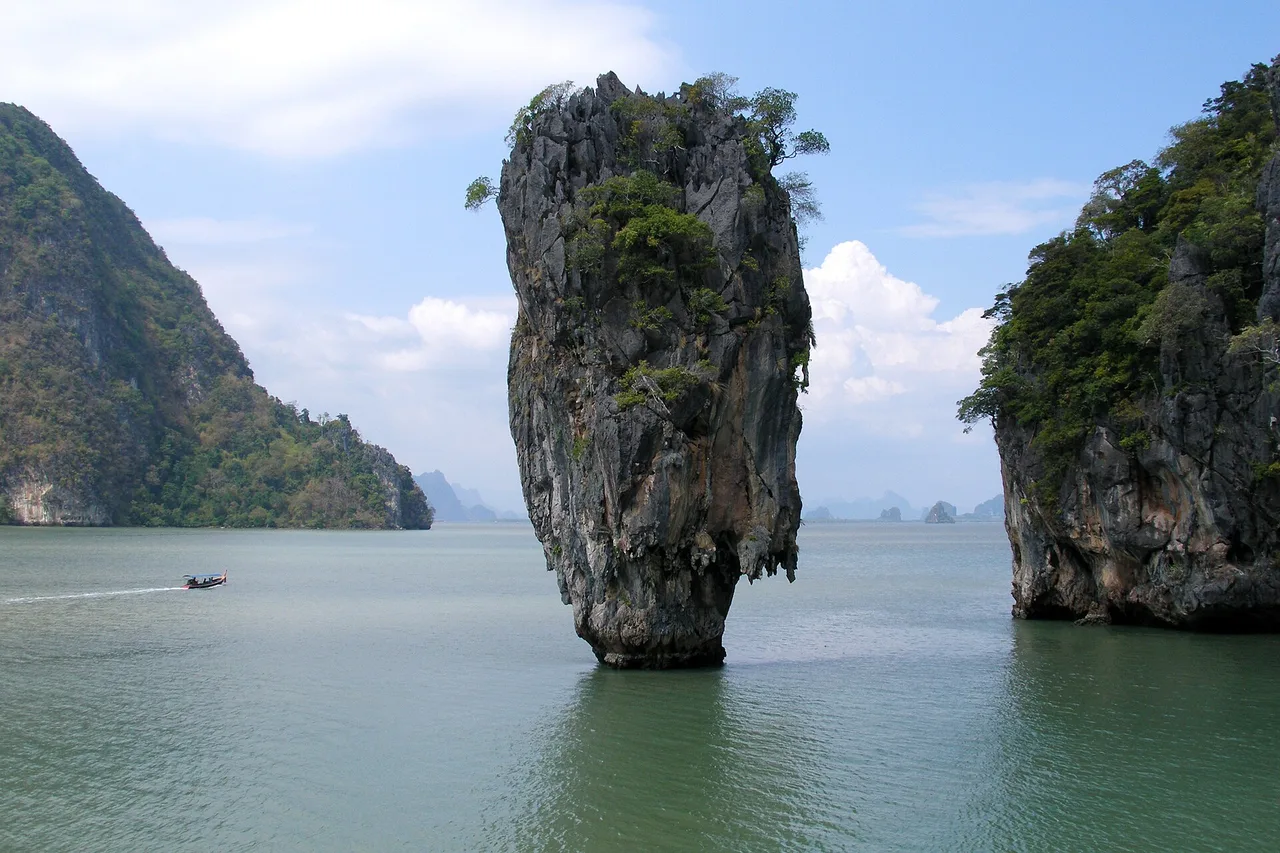 L’aiguille rocheuse de Ko Tapu, dite James Bond Island, émerge d’une eau verte de la baie de Phang Nga, entre deux falaises calcaires couvertes de végétation sous un ciel clair