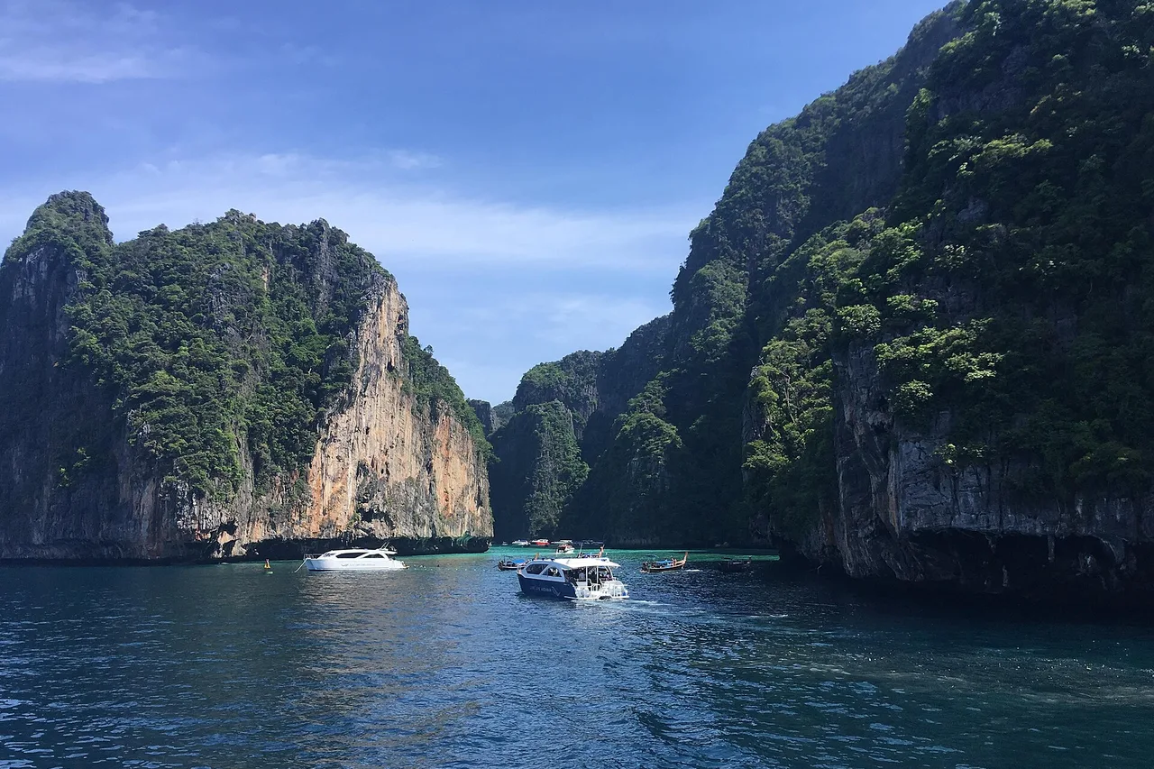 Le lagon de Pileh sur Ko Phi Phi Le : plusieurs bateaux rapides sur une eau bleu profond entre des falaises calcaires abruptes couvertes de végétation
