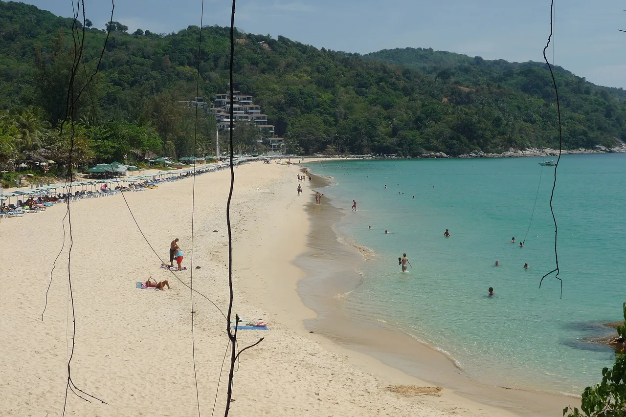 Der helle Sandstrand von Kata Beach mit türkisfarbenem Wasser und grünen Hügeln im Hintergrund