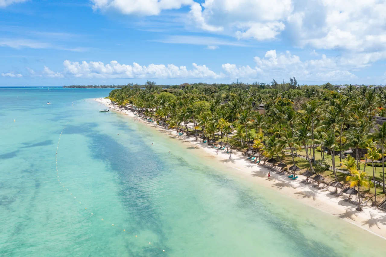 Die türkise Lagune und der von Kasuarinen gesäumte Strand von Trou aux Biches aus der Luft