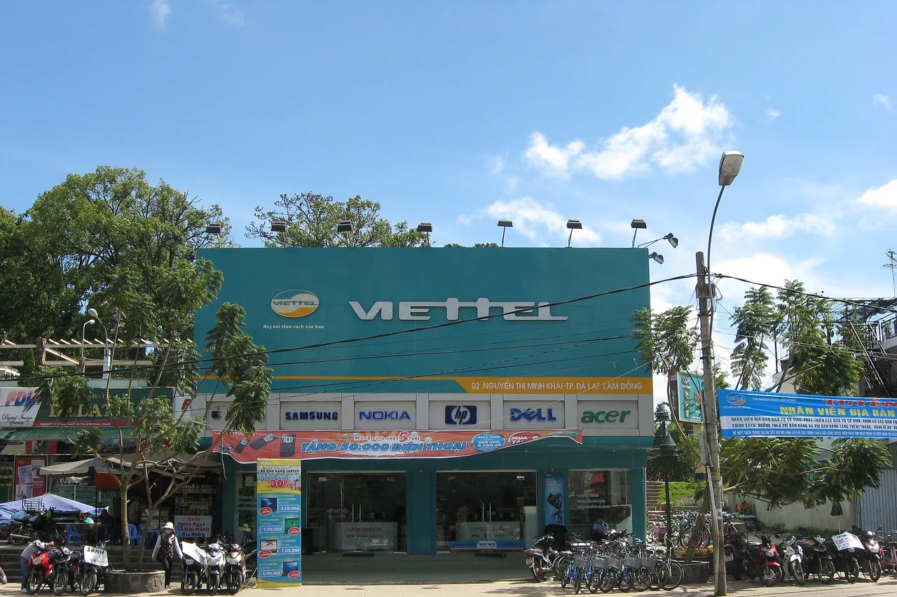 Boutique Viettel à Dalat : façade turquoise au logo rouge, scooters et arbres devant, ciel bleu