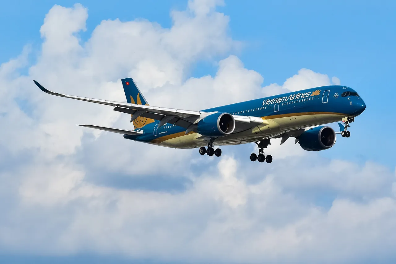Ein Airbus A350-900 von Vietnam Airlines im Landeanflug mit ausgefahrenem Fahrwerk vor blauem Himmel mit Wolken