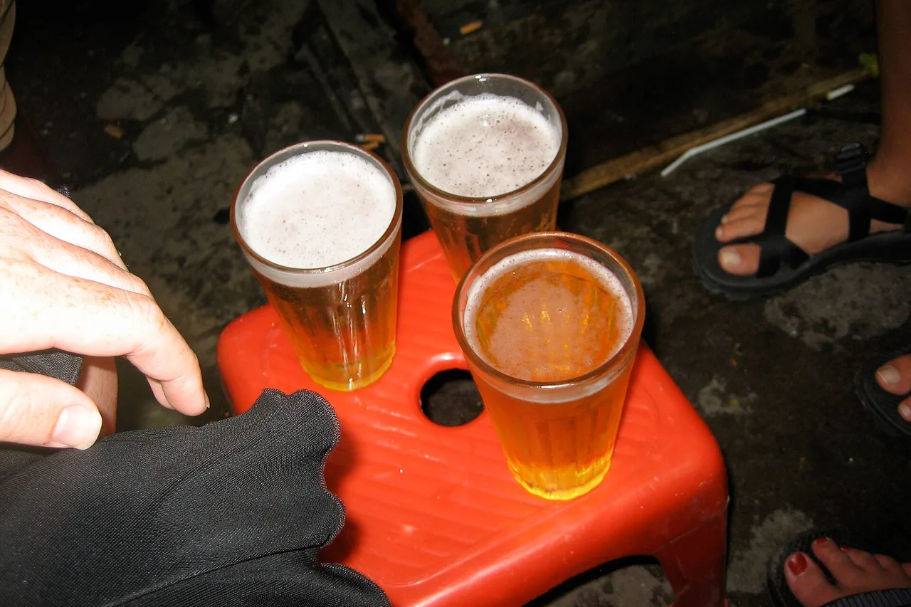Tre bicchieri di bia hơi, la birra alla spina locale, su un piccolo sgabello di plastica rosso su un marciapiede di Hanoi