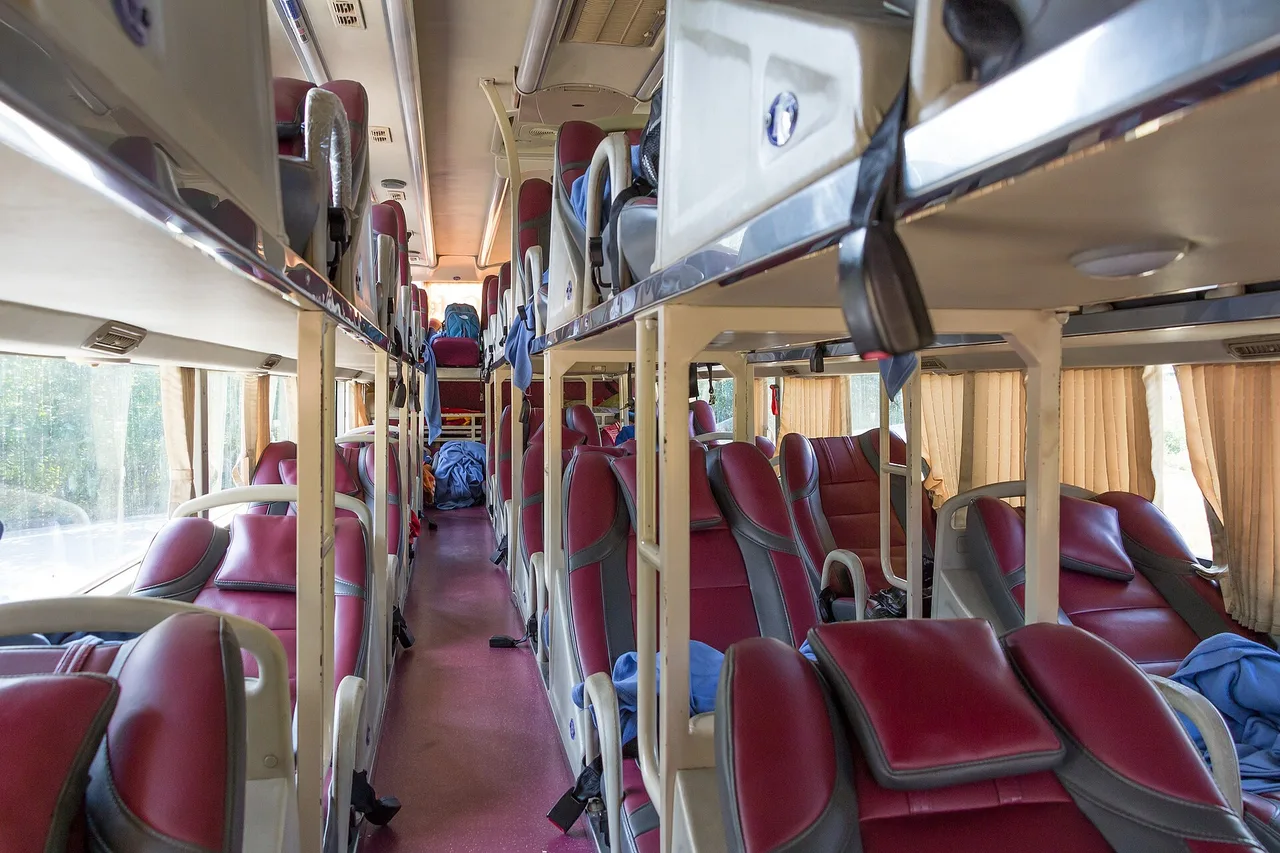 L’interno di un autobus con cuccette vietnamita: due piani di posti reclinabili rossi lungo un corridoio centrale