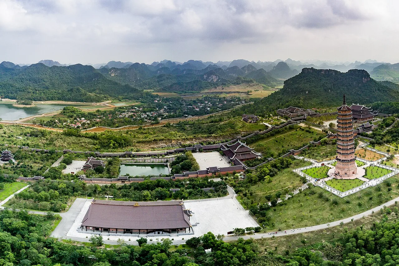 Aerial view of Bai Dinh pagoda with its tall tower, halls and gardens among limestone hills