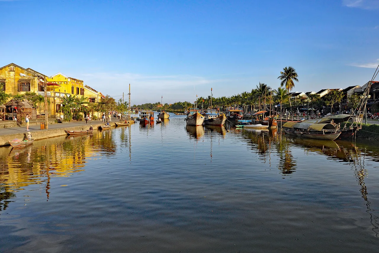 Maisons jaunes et barques en bois au bord de la rivière Thu Bồn à Hội An sous un ciel clair