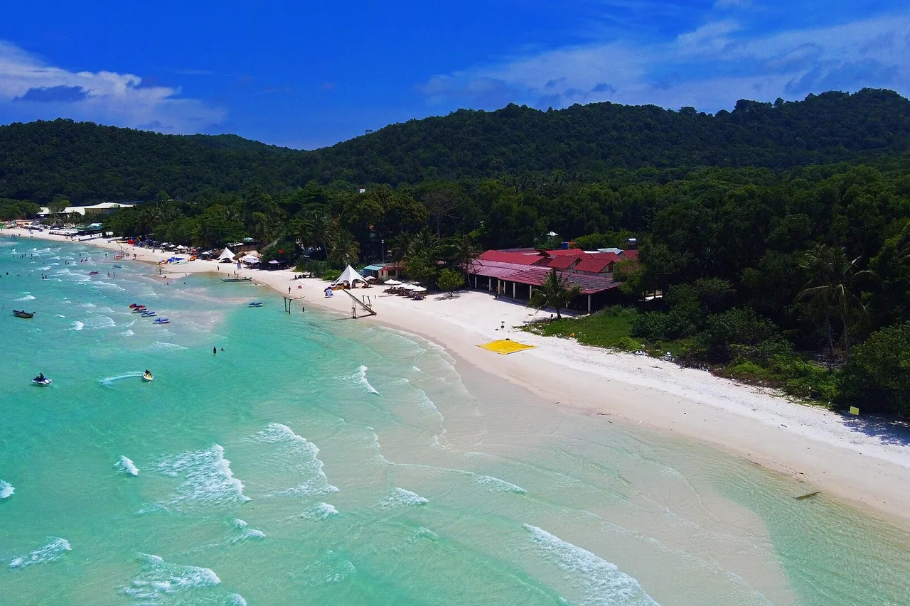 Eau turquoise et plage de sable blanc de Bãi Sao à Phú Quốc, collines boisées derrière